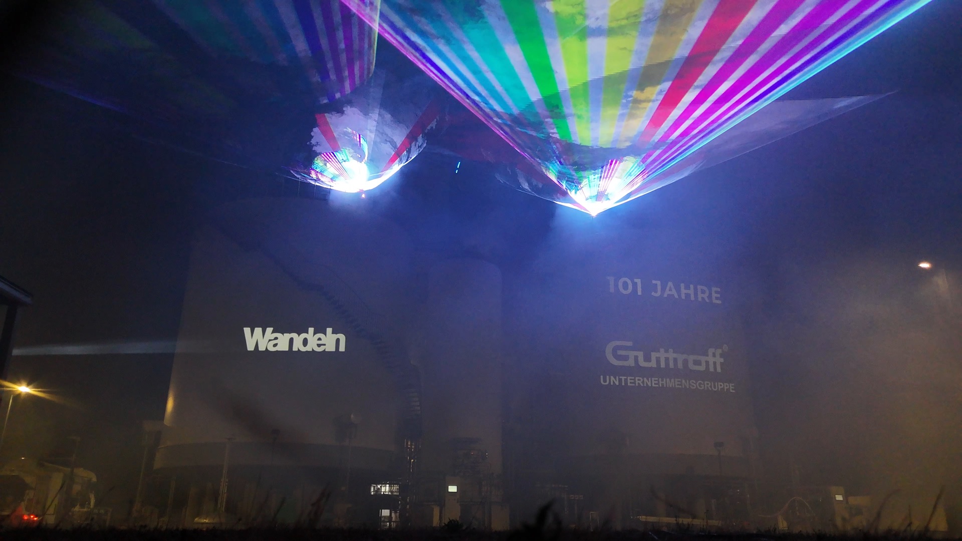 Laserfächer über einer Industrieanlage bei Nacht