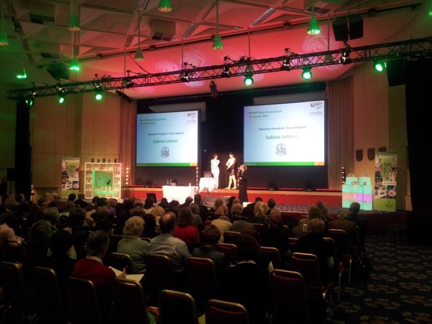 Kick-off-Veranstaltung mit vollem Saal, Bühne und zwei Projektionsflächen