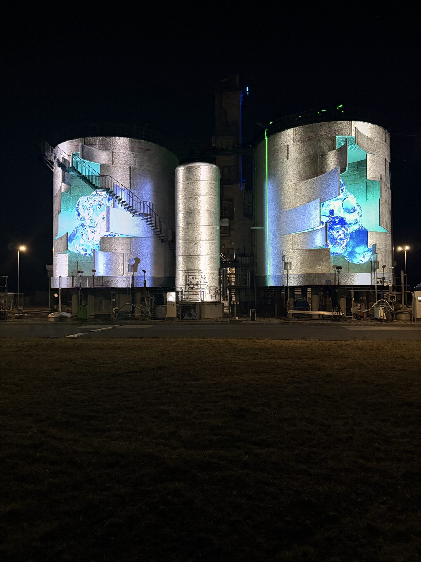 Videomapping auf zwei Tankbehältern einer Industrieanlage bei Nacht