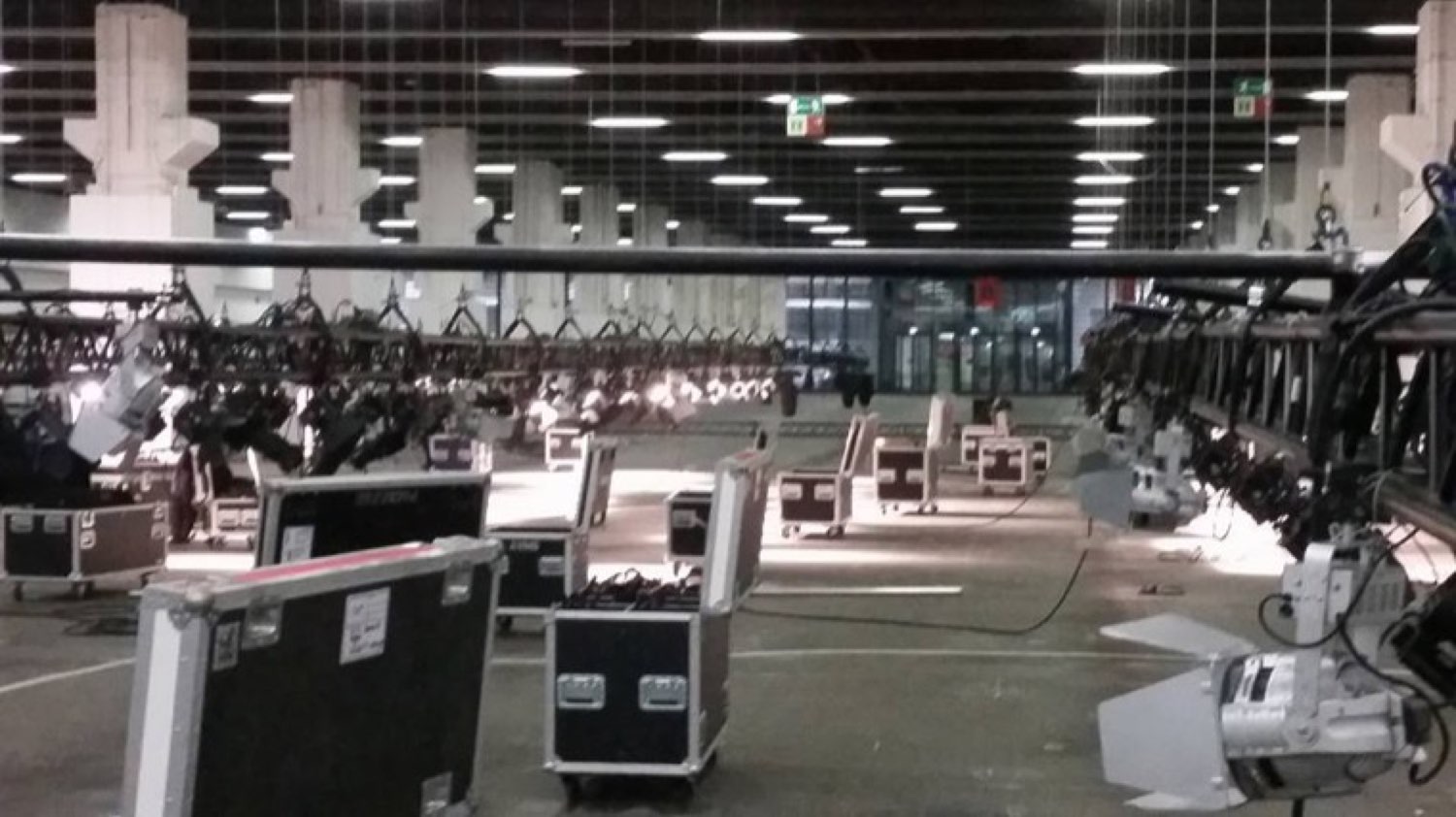 Halle mit hallenweitem Traversensystem und montierten Moving Lights, davor Flightcases