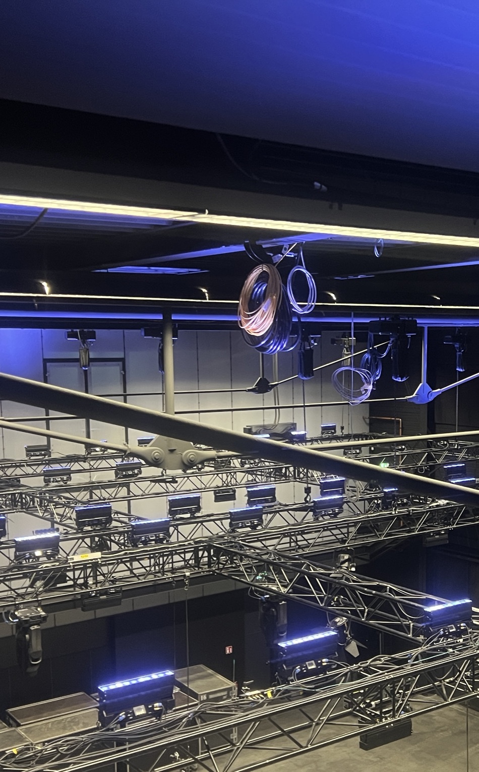 Traversen mit LED-Leisten und Kabelringen in einer Halle von oben